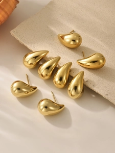 Macro shot of minimalist gold teardrop earrings showing smooth polished metal surface