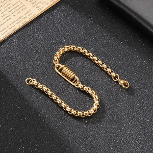 Bracelet chaîne box punk doré avec ressorts et fermoir mousqueton sur fond noir mat