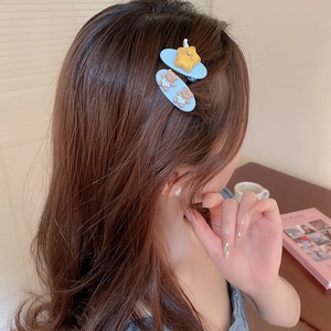 Détail de deux jolies pinces à cheveux bleues avec ours et étoile sur cheveux bruns