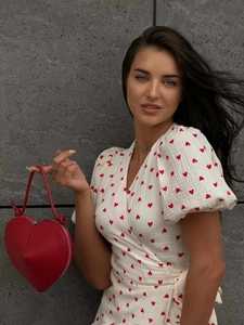 Detail of red heart patterns on white cotton wrap dress with a matching heart clutch bag