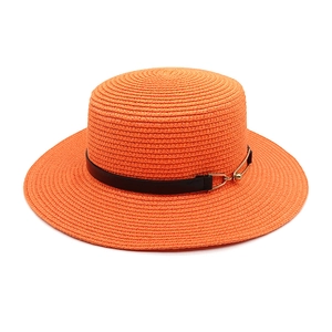 Detail of orange flat top straw hat with black leather band and golden metal buckle