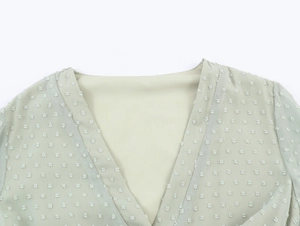Gros plan détaillé d'une robe en mousseline vert clair avec col en V et motifs en jacquard