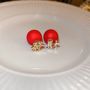 Macro view of Chinese New Year earrings with red beads and golden 'Fa' and 'Cai' charms