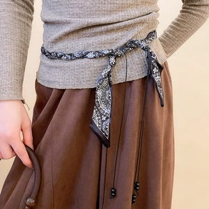 Detail of vintage paisley pattern scarf belt with pearl beads on a neutral outfit