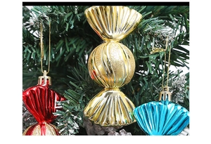 Close-up of colorful metallic candy ornaments hanging on a green Christmas tree