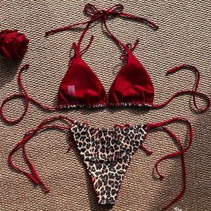 Red halter bikini top with leopard print tie-side bottoms on a woven straw mat