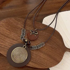 Bohemian double-layer necklace with wooden pendants and golden bow on a rustic tray