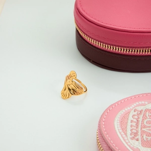 Detail view of a gold butterfly open ring with textured wings on a pink jewelry box