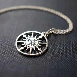 Macro detail of silver Viking compass pendant with engraved NSEW markers on dark texture
