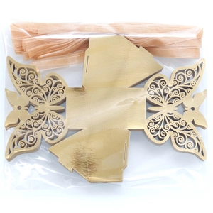 Flat lay of laser-cut butterfly candy box pieces with gold ribbons for party favors