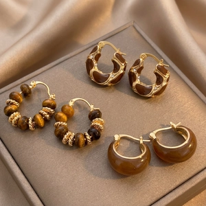 Macro view of tiger eye stone earrings and vintage amber studs on luxury silk texture