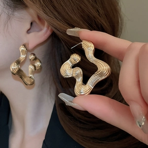 Irregular golden wavy geometric stud earrings in minimalist metallic design for women