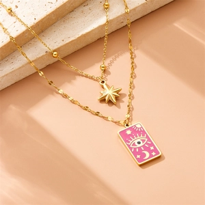 Close-up of double layer gold necklace featuring star and tarot eye pendant on stone