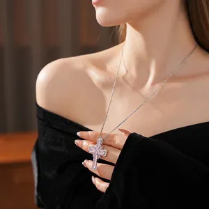 Silver cross pendant necklace with pink zircon crystals worn by a model on black velvet