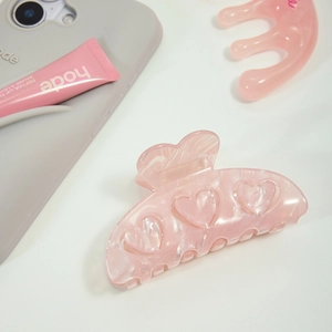 Détail d'une pince à cheveux en acétate rose avec motifs cœurs et texture marbrée