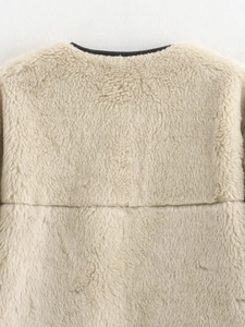Detailed close-up of cream faux shearling texture with black leather piping trim