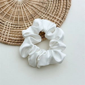 Detailed view of the smooth white satin fabric and pleated texture of the hair scrunchie