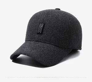 Detail of dark grey wool-like baseball cap featuring ear flaps and leather fashion patch