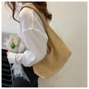 Chic beige woven straw hobo bag with khaki leather straps carried by a model on shoulder
