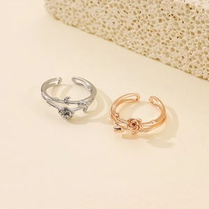 Close-up of adjustable silver and rose gold flower rings with leaf design details