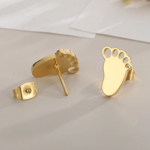Macro view of gold paw print stud earrings with stainless steel posts and backings