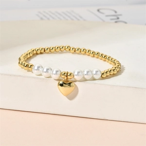 Detail of beaded bracelet with gold copper beads, white pearls and heart pendant