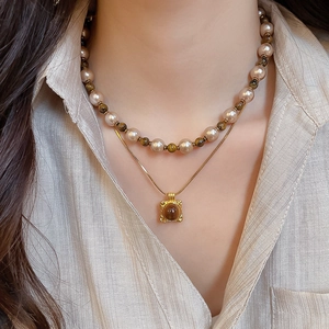 Detailed view of layered necklace with tiger eye beads and square vintage gold pendant