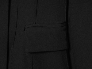 Vue détaillée d'un blazer noir avec poche à rabat et texture de tissu tissé