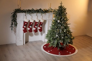 Détail de la jupe de sapin rouge tricotée et des chaussettes de Noël brodées assorties