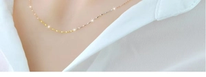 Dettaglio di una collana a catena a labbra dorata minimalista indossata da una modella