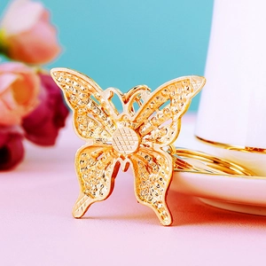 Close-up of golden butterfly keychain with intricate hollow carving and diamond details