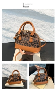 Detail view of brown leopard print shell bag with premium leather handles and golden zippers
