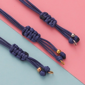Détail du bracelet en cordon de cire tressé bleu foncé avec perles en métal et nœud ajustable