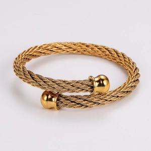 Detailed close-up of golden woven cable wire bracelet with spherical end caps