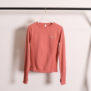 Close-up of coral pink long sleeve sports top with thumbhole cuffs and AMI MEDEA logo