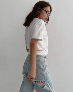 Détail du jean bleu clair à taille haute avec de larges déchirures pour femmes
