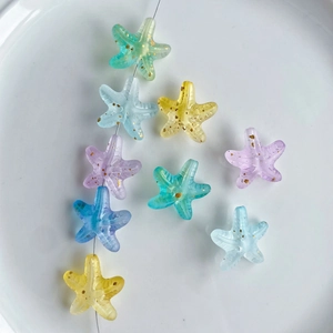 Colorful gradient acrylic starfish beads with gold glitter in a white ceramic tray