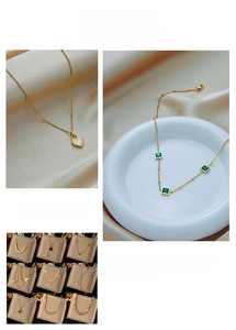 Detail of gold layered necklaces with butterfly, heart, and green gemstone pendants