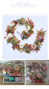 Close-up of autumn garland featuring faux maple leaves, pumpkins and white dahlias