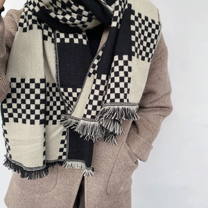 Thick checkered scarf in beige and black with tassels worn over a winter coat