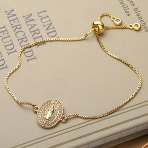 Adjustable gold Virgin Mary bracelet with zircon inlay and sliding ball clasp on vintage book