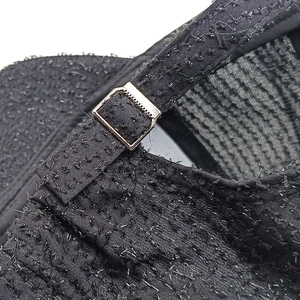 Close-up of black baseball cap metal buckle and textured fabric with silver threads