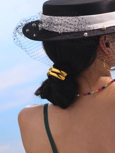 Close-up of golden curved metal hair tie accessory on elegant low ponytail