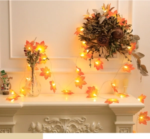 Close-up of LED maple leaf string lights glowing warmly around a vase on a mantel