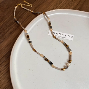 Beaded necklace with agate and wood beads displayed on a white tray with golden lobster clasp