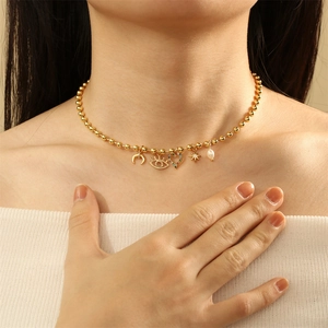 Detailed close-up of gold beaded necklace with evil eye and pearl charms on a model