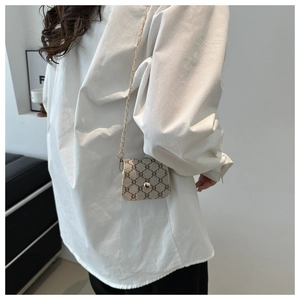 Detail of mini square bag with beige monogram pattern and golden chain strap