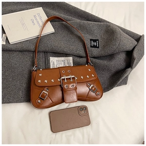 Detail shot of brown punk shoulder bag featuring silver rivets and metal belt buckles