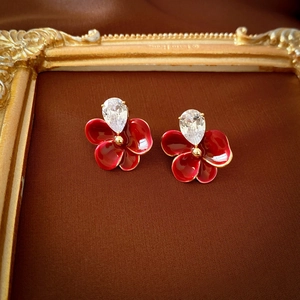 Détail d'une boucle d'oreille fleur rouge avec zircon sur un cadre doré vintage
