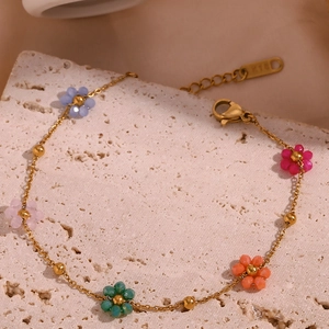Macro detail of gold-plated chain bracelet with colorful beaded flower charms and K18 tag